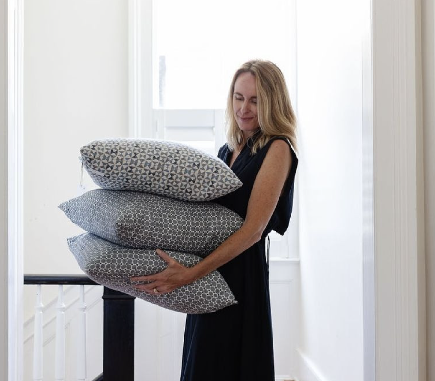 Emily Daws holding a stack of patterned pillows