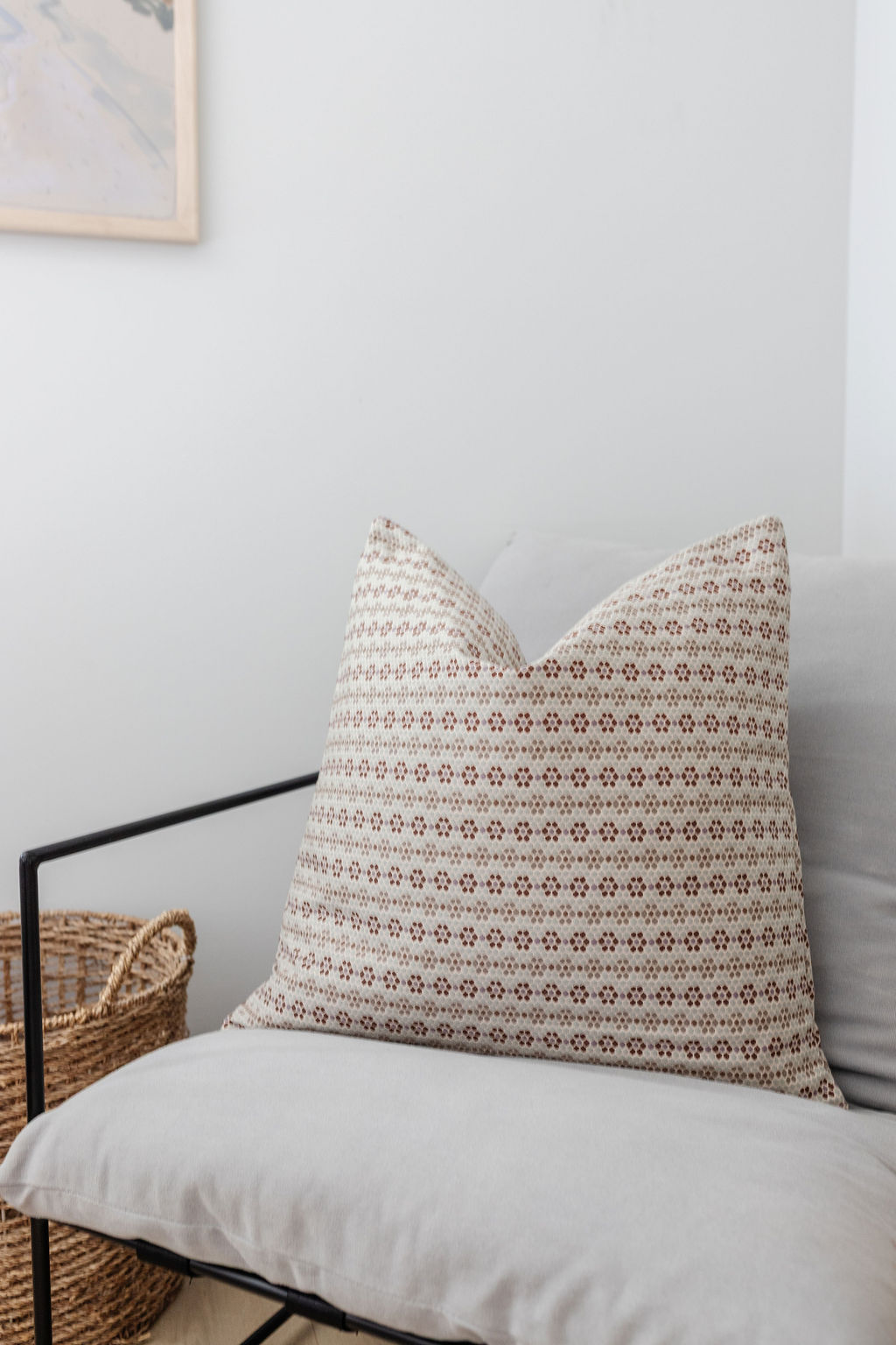 A Nectar in Sugar Plum pillow on a modern black-framed chair, the geometric floral motif in warm brown on cream