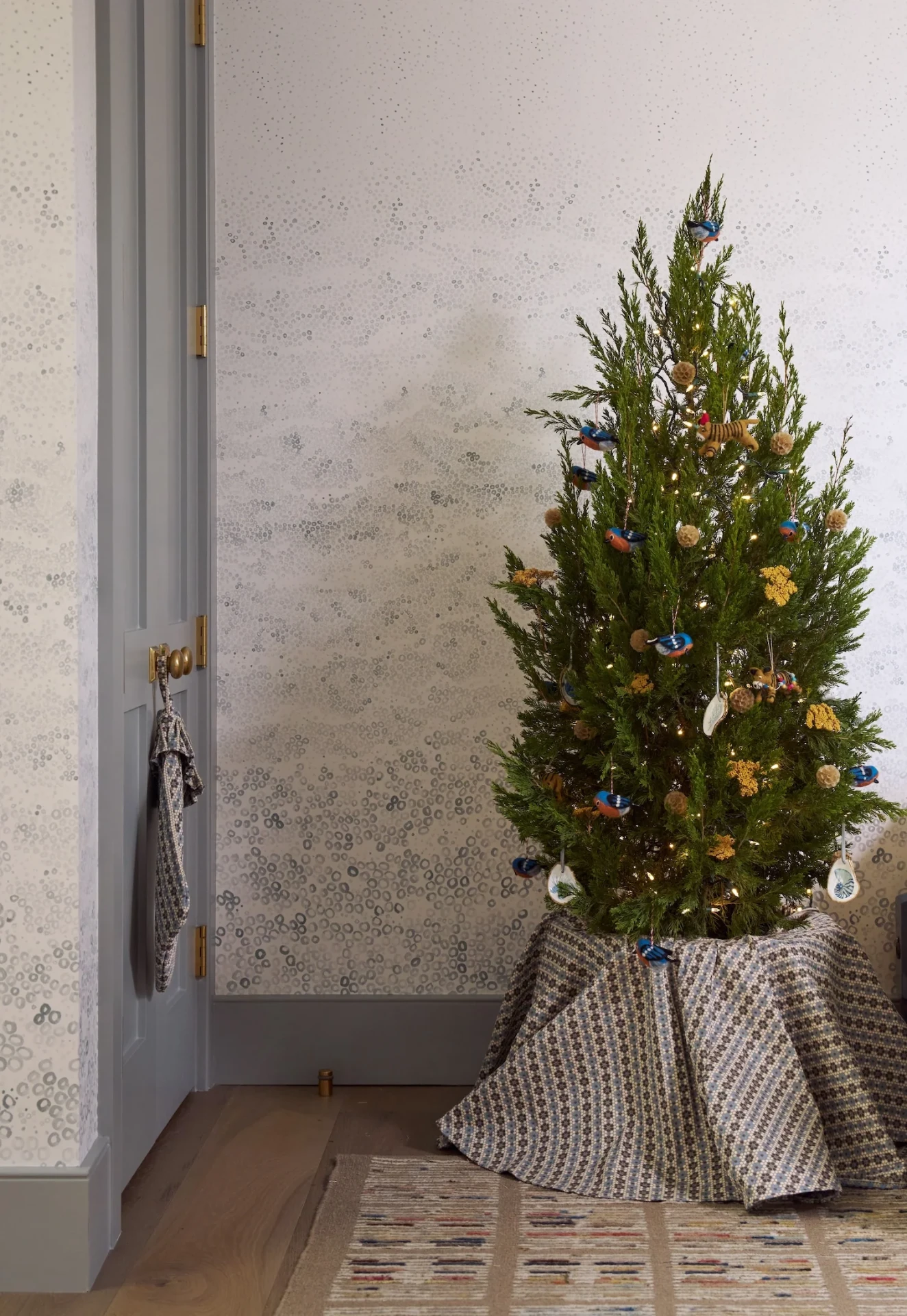 Christmas tree with a patterned Nectar tree skirt in a corner