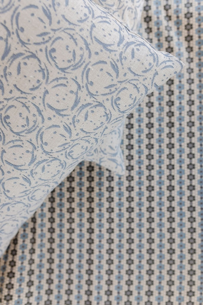 Blue patterned pillow against a small-scale geometric wallcovering
