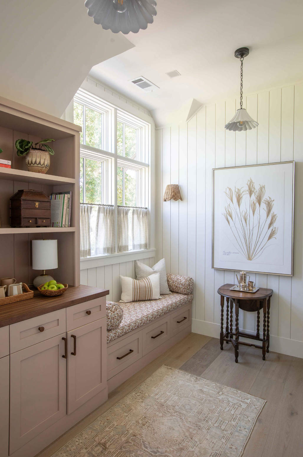 A sunlit window seat layered with linen cushions and a woven throw as the evening light lowers